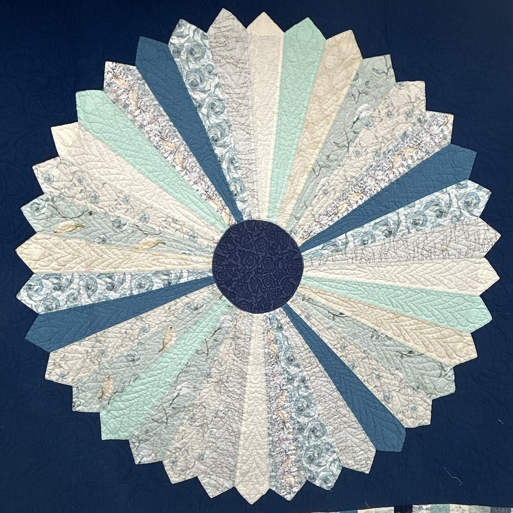 The Dresden plate quilt itself: twenty wedges in cream, sea green, pale blue florals and slate on a navy ground, hanging in the studio