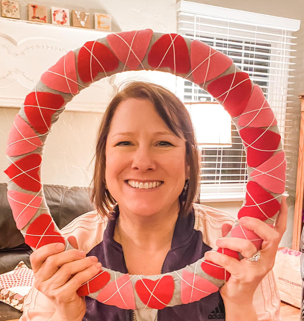Ellen of Auburn Sewing Studio holding a felt heart wreath she made