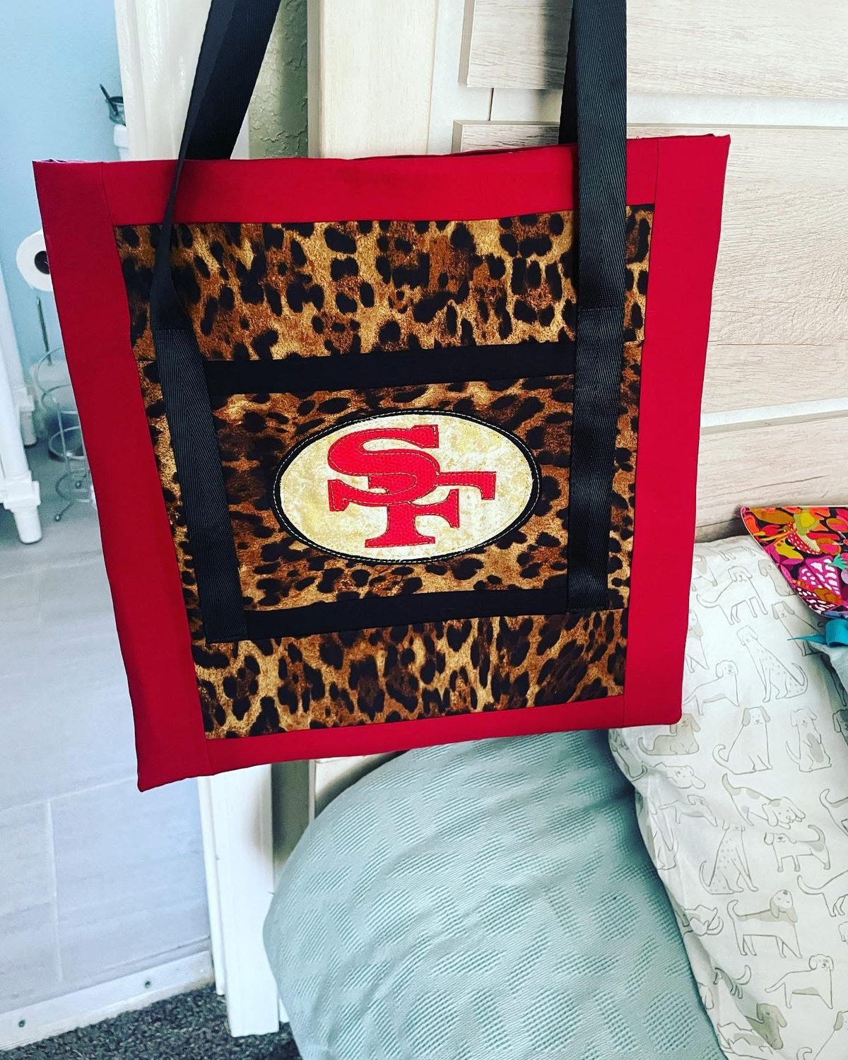 A red tote bag with a leopard print panel and an appliqued SF oval, made at the studio